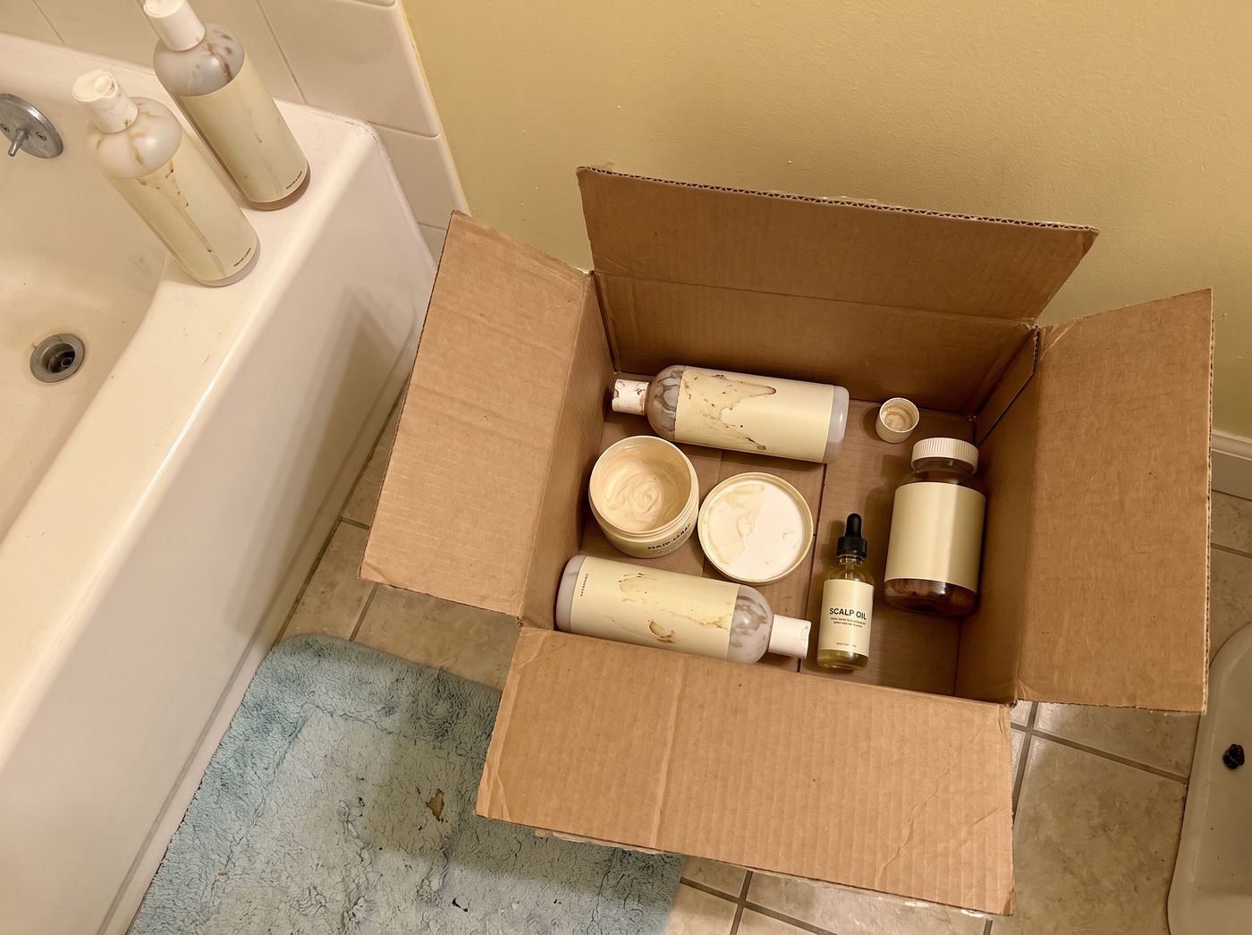 A box of half-used hair products being thrown out
